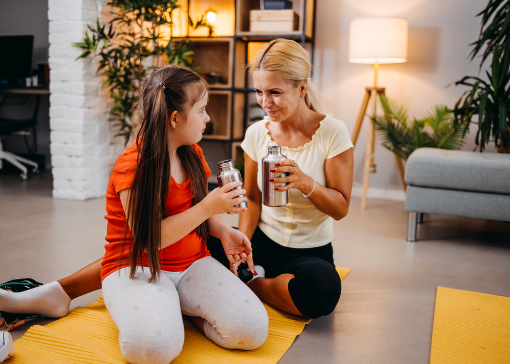 Woman comforting her daughter on the spectrum and giving her a glass of water to hydrate