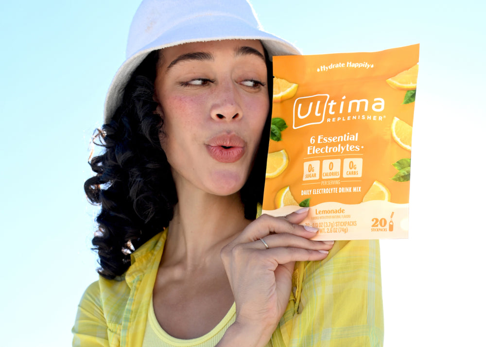 Woman holding package of Ultima Lemonade Electrolyte Mix